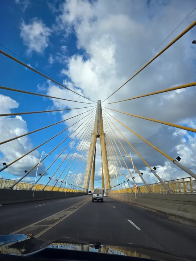 Atravessando a ponte sobre o Rio Negro, os cabos abrindo em leque contra o céu de Manaus