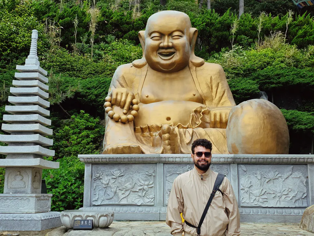 Diante do Buda dourado, o Laughing Buddha, no templo Haedong Yonggungsa