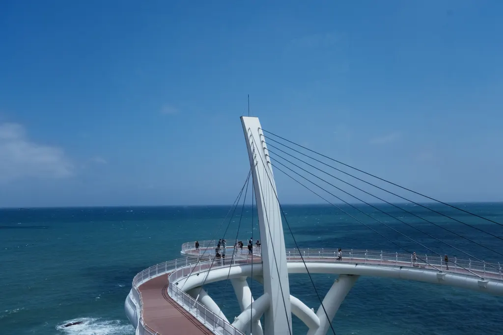 A passarela branca estaiada fazendo uma curva sobre o mar, em Cheongsapo